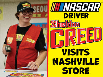 NASCAR driver Sheldon Creed smiles while visiting Ollie's store in Nashville, engaging with fans and showcasing merchandise.